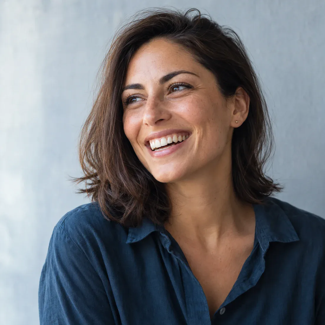 A naturally smiling woman in soft daylight — illustrative brand portrait